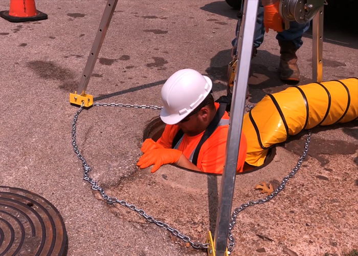 Worker Entering A Confined Space With Tripod And Blower