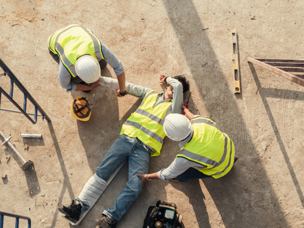 Workers Administering First Aid To A Fallen Worker